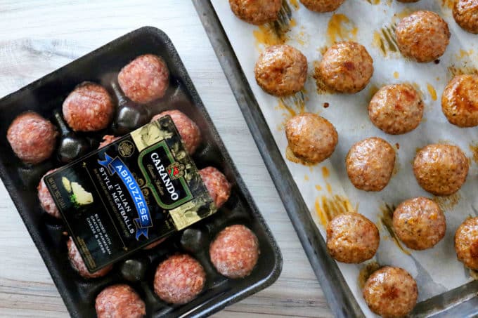 An overhead shot of cooked meatballs on a baking pan along with a package of uncooked meatballs. 