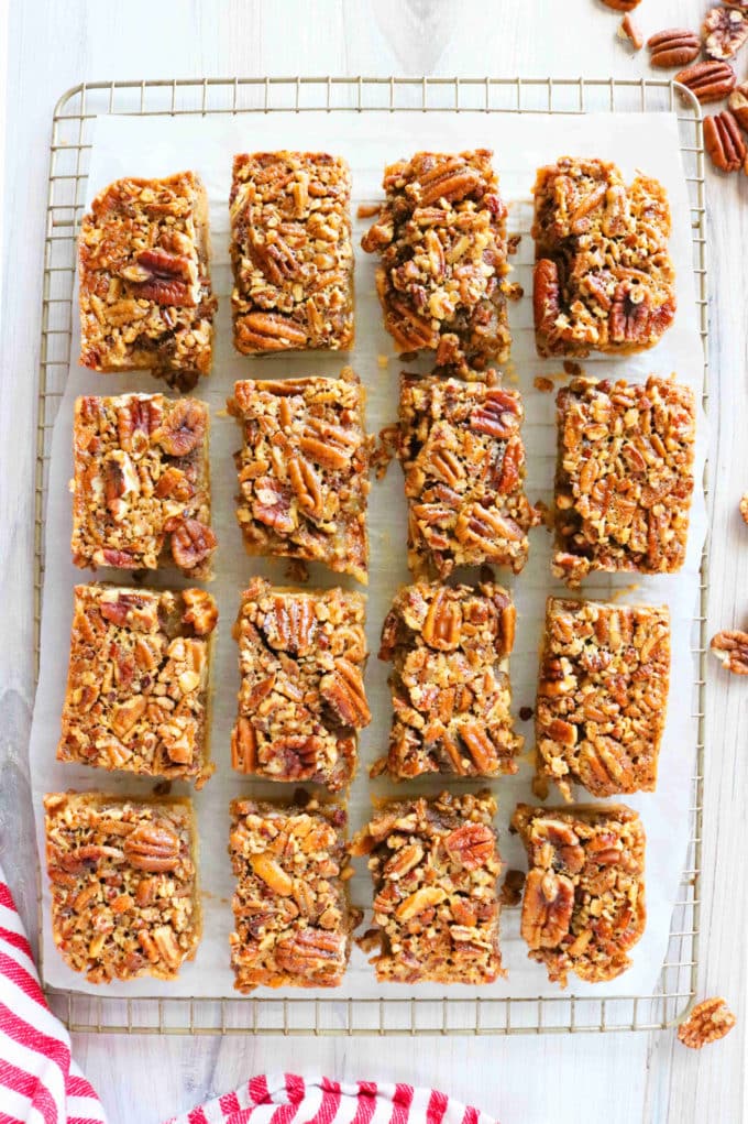 An overhead shot of sliced Pecan Pie Bars a parchment paper that is on top a wire cooking rack. 