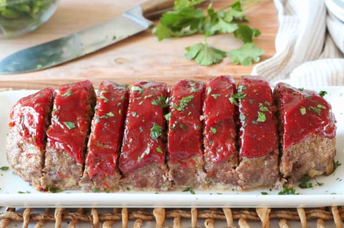 A side view of sliced Southern Meatloaf served on a white plate. 