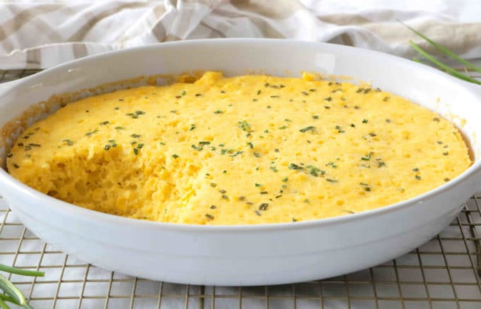 A side shot of Corn Souffle with a spoonful missing from the white oval dish. 