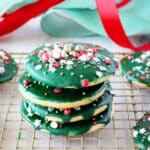 A stack of iced sugar cookies on a cooling rack with ribbon in the background.
