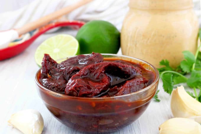 Chipotle peppers in adobo sauce with limes and garlic surrounding it.