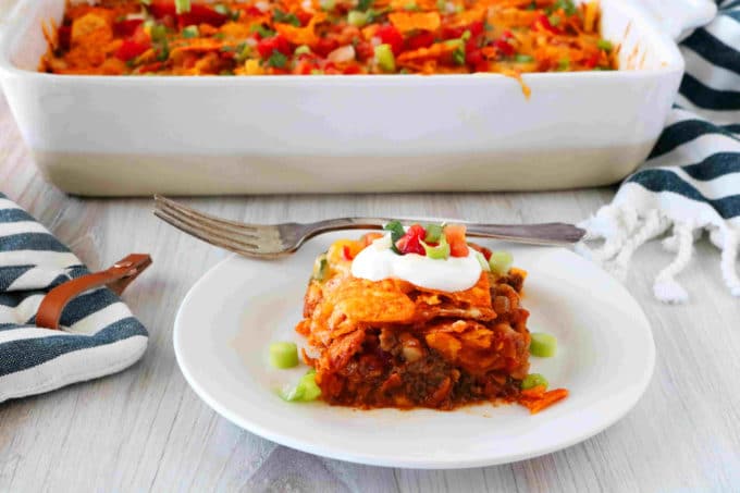 Doritos casserole on a plate in front of a casserole dish.