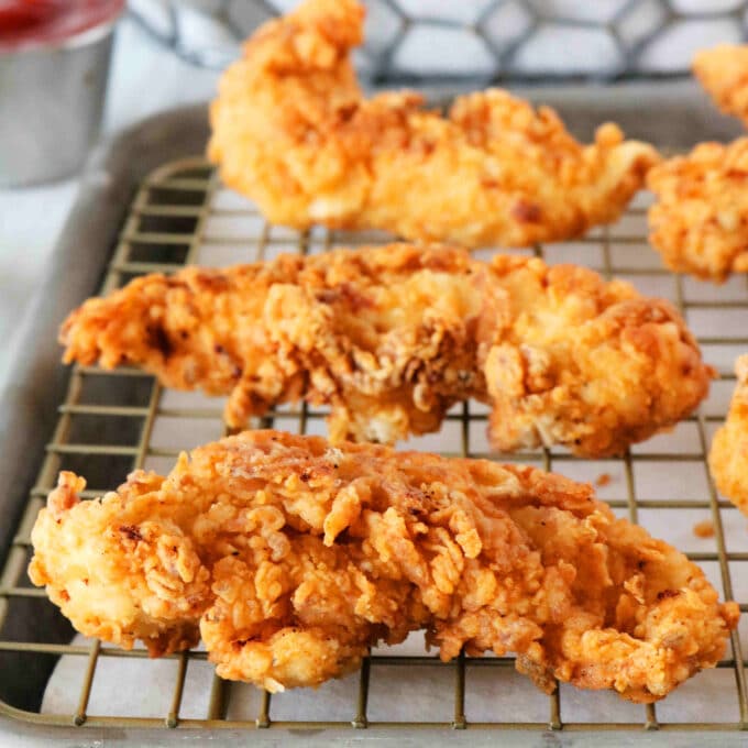 A close-up shot of fried chicken strips on a cooling rack.