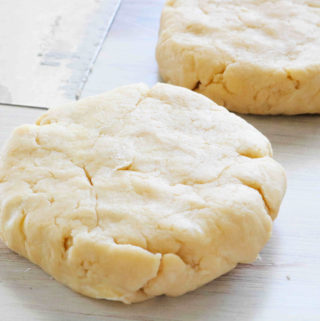 Pie crust pastry disks with a bench scraper off to the side.