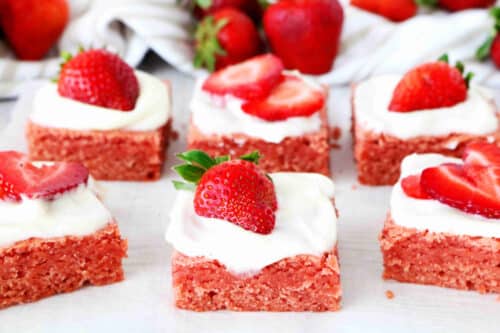 Strawberry brownies topped with icing and halved strawberries.