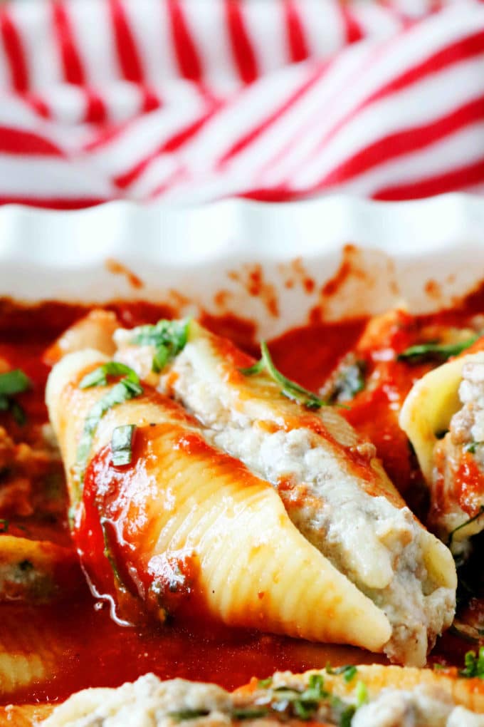 A close up shot of stuffed shells with meat and ricotta in a casserole dish.