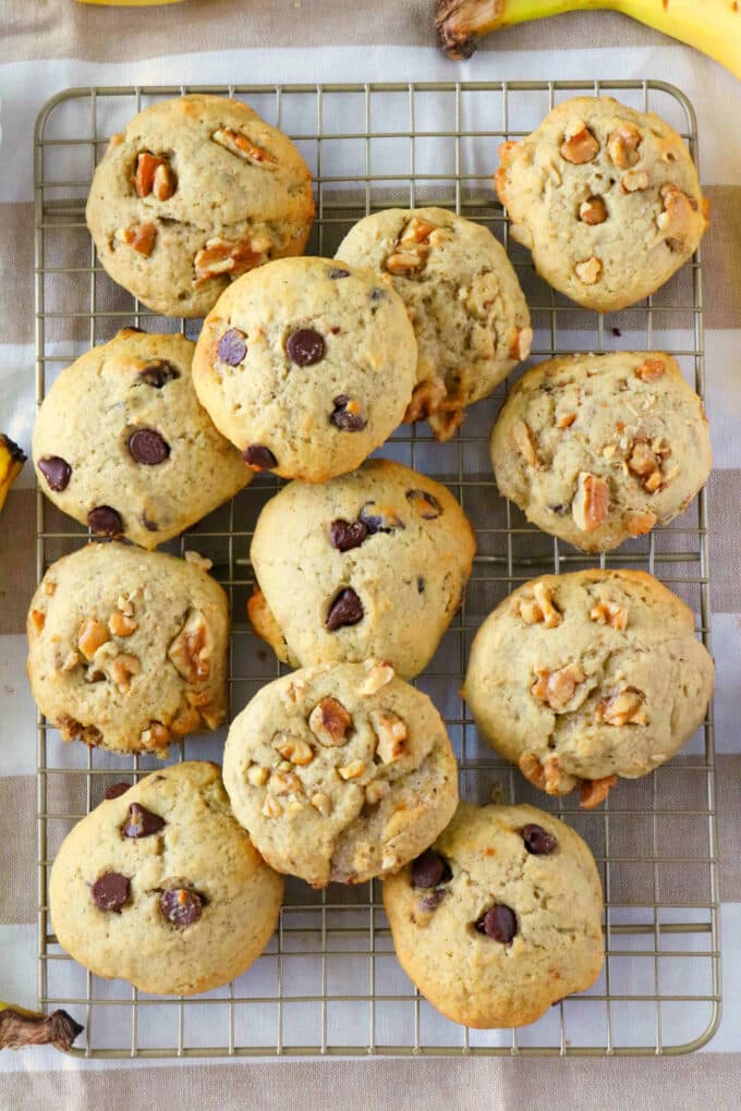 Walnut banana cookies and banana cookies with chocolate chips spread out on a cooling rack.