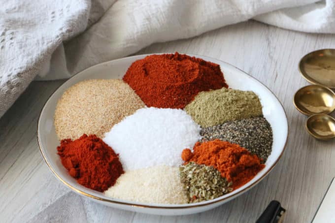 All of the different spices you would see in blackened seasoning laid out separately on a plate.
