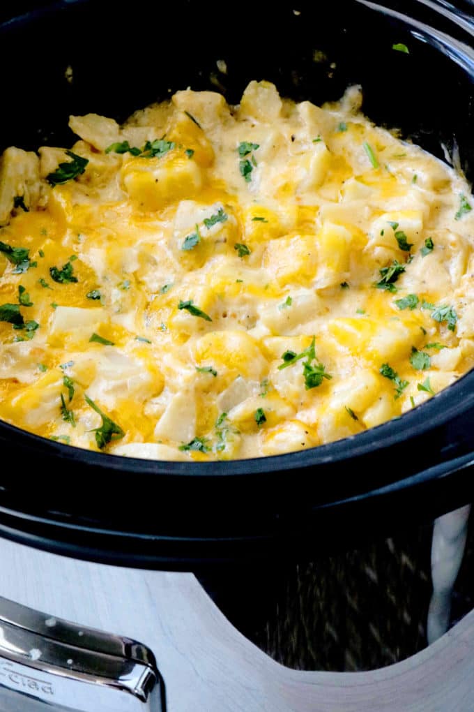 Cheesy Crockpot potatoes in a slow cooker sprinkled with parlsey.