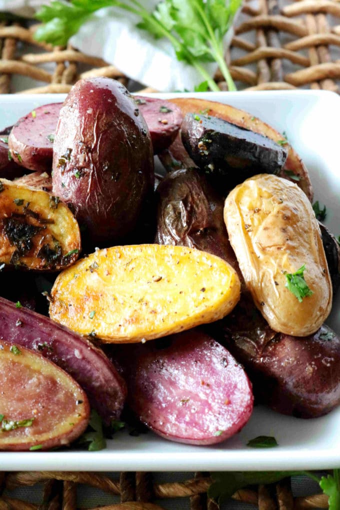 Fingerling potatoes on a white platter with parsley in the background.