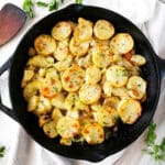 Potatoes Lyonnaise in a cast iron skillet with parsley scattered around.