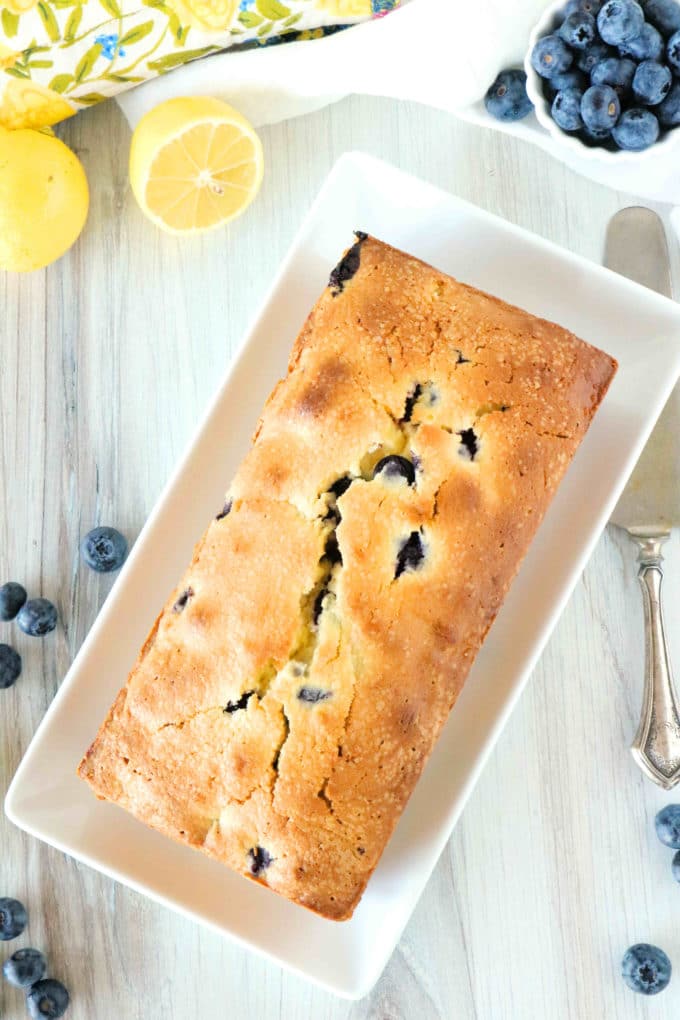 An overhead shot of blueberry pound cake on a platter with a knife off to the side. 
