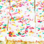 Sliced cake in a 9x13" casserole dish topped with vanilla icing and sprinkles.