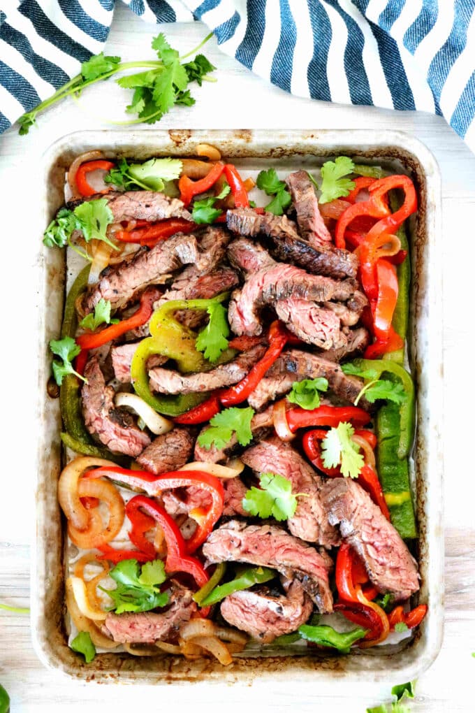 An overhead shot of beef mixed with white, red, and green fajita veggies.