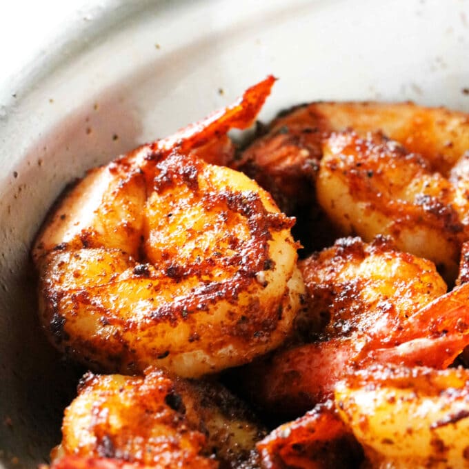 Blackened Shrimp cooked in a saute pan with butter in the bottom of the pan.