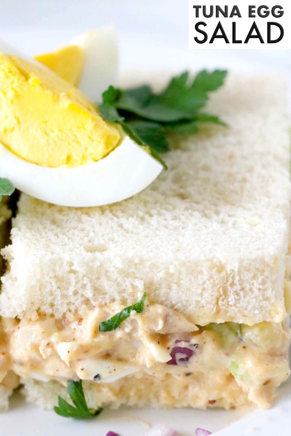 Image for Pinterest. Tuna egg salad piled between two slices of fluffy white bread. Topped with an egg.