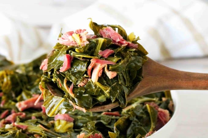 Collared Greens on a spoon with shredded ham hock on top.