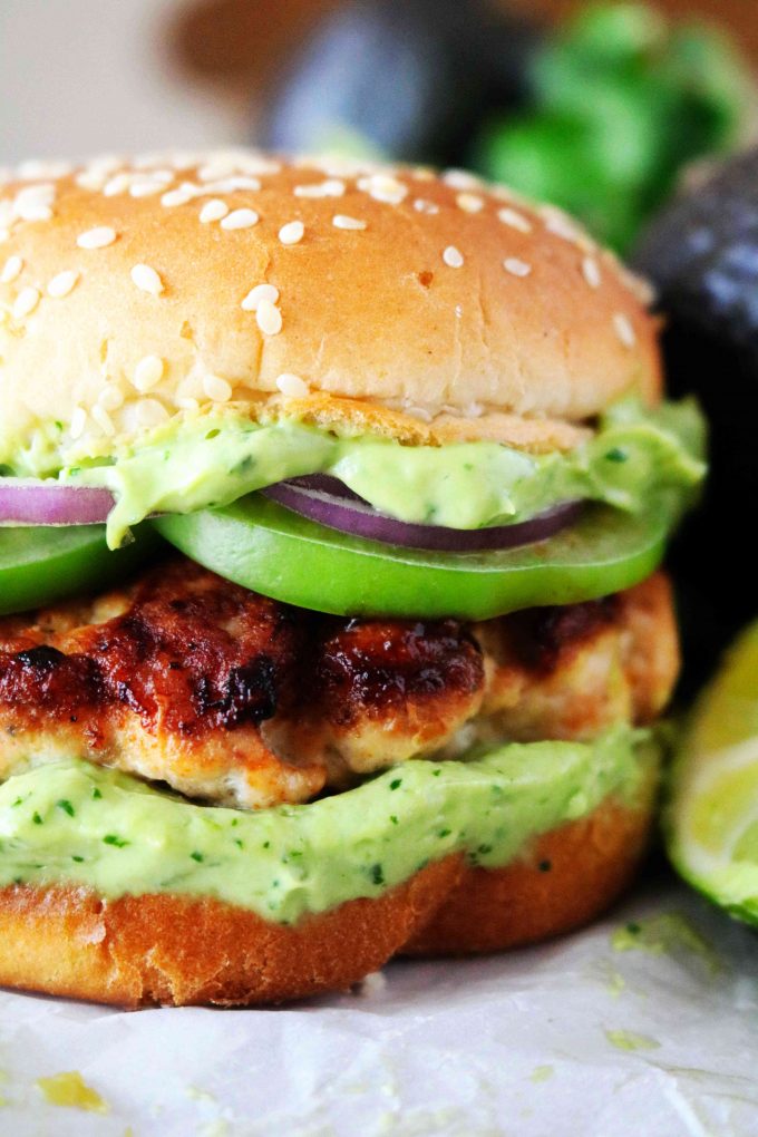 A close up shot of a green chili turkey burger with sauce dripping out of the sides.
