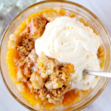 An overhead shot of a bowl full of old fashioned peach cobbler with ice cream on top.