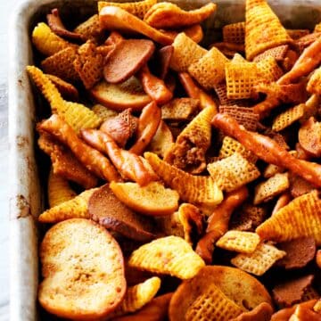 Different types of Chex cereal, pretzels, bagel chips, bugels, and rye chips on a sheet pan.