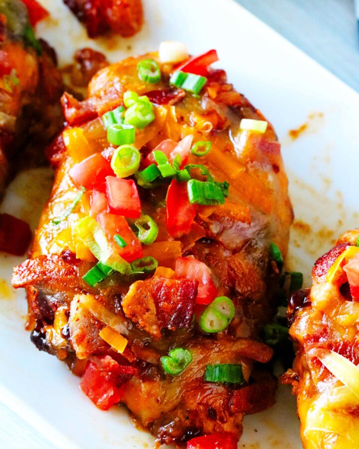 An overhead shot of Monterey Chicken on a platter topped with tomatoes and green onions.