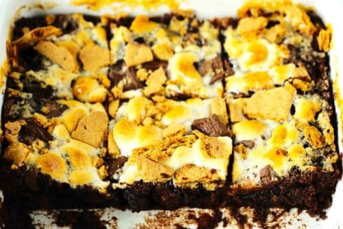 S' mores brownies in a baking pan, with three brownies removed so you can see the brownie base and s' mores topping.