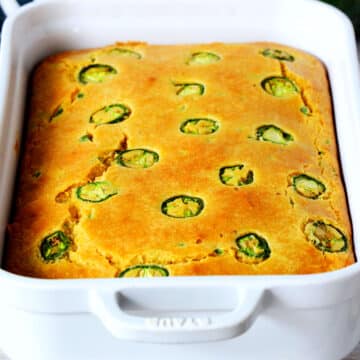 Jalapeno Cheddar Cornbread in a white casserole dish with jalapenos on top.