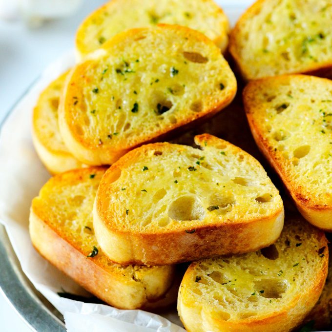 Garlic bread toast in a silver dish with a white napkin liner.