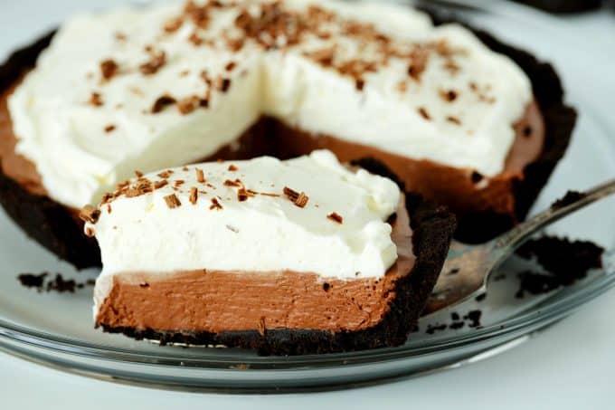 A slice of no bake chocolate pie with a whole pie behind it.