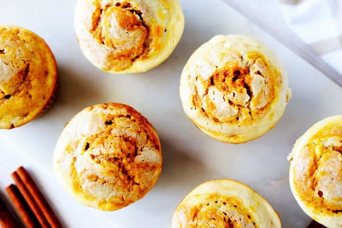 An overhead shot of cream cheese pumpkin muffins on a marble board.