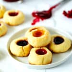 Thumbprint cookies on plate with a spoonful of jam in the background.