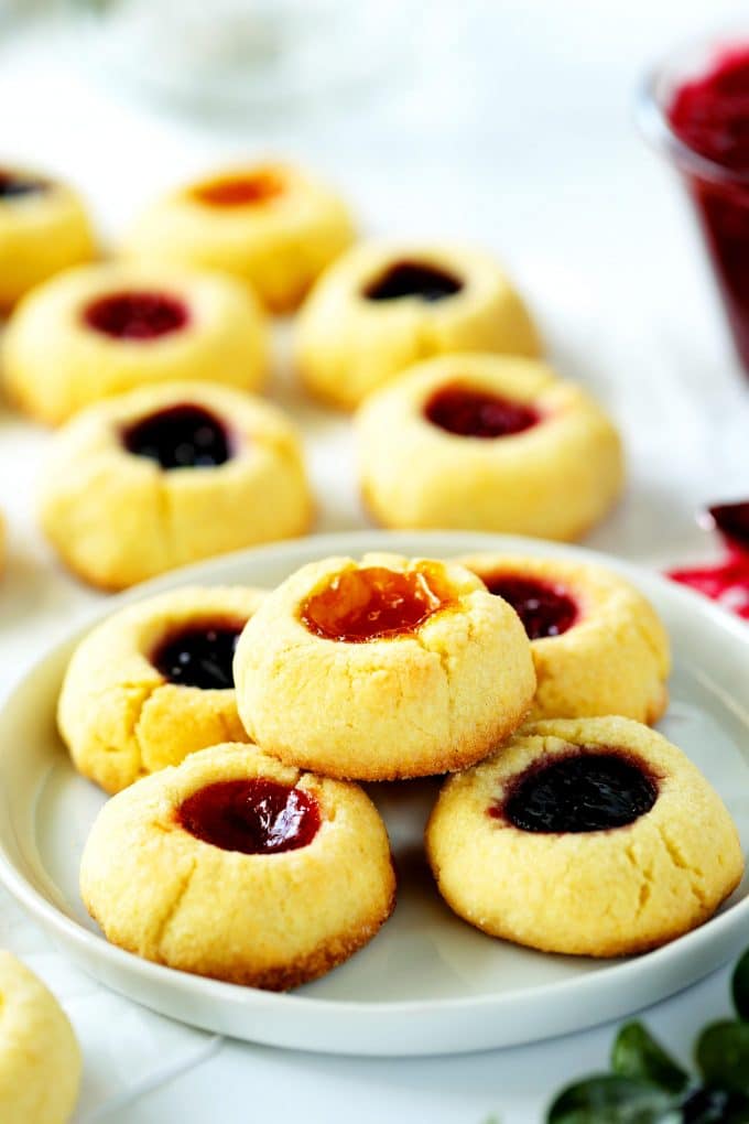 Thumbprint Cookies with Jam on a plate with cookies in the background.