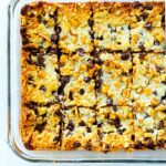 An overhead close up shot of 7 Layer Magic Bar Cookies cut into bars in a casserole dish.