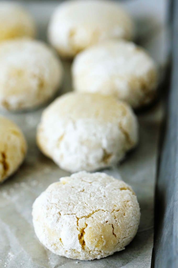 Amaretti cookies dusted with powdered sugar on a baking sheet.