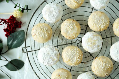 An overhead shot of Italian Wedding Cookies, some with icing and other rolled in powdered sugar, on a rack.
