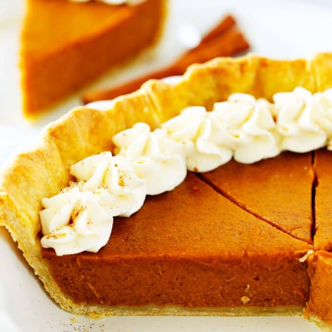 Sweet potato pie in a pie dish with slices cut out of it.