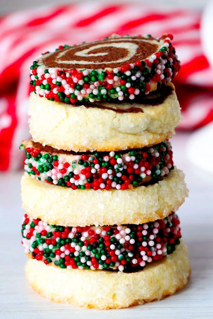 A stack of Christmas pinwheel cookies with a checkered red towel behind it.