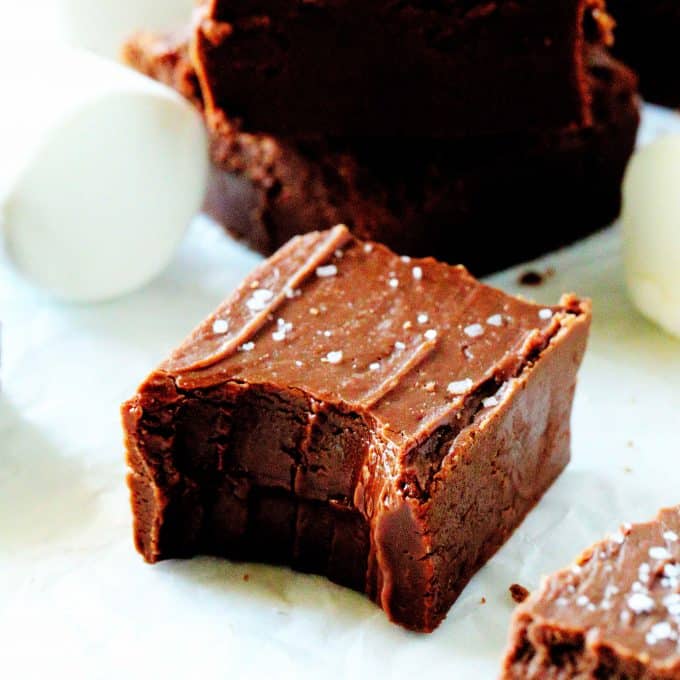 Marshmallow fudge on a white surface with a bite taken out of it.
