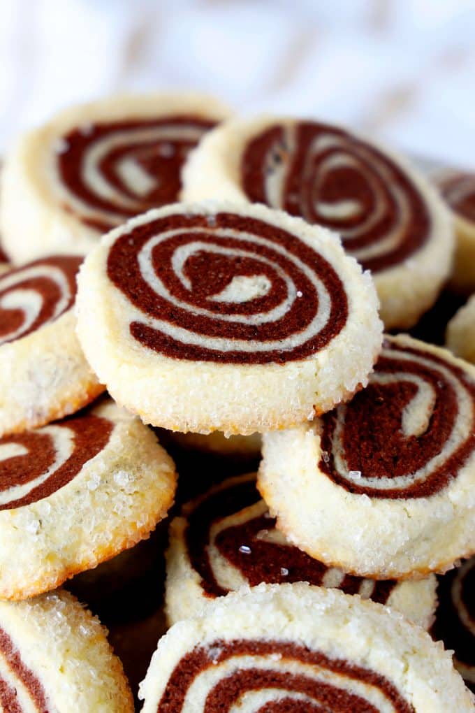 A close up shot of a stack of chocolate pinwheel cookies .