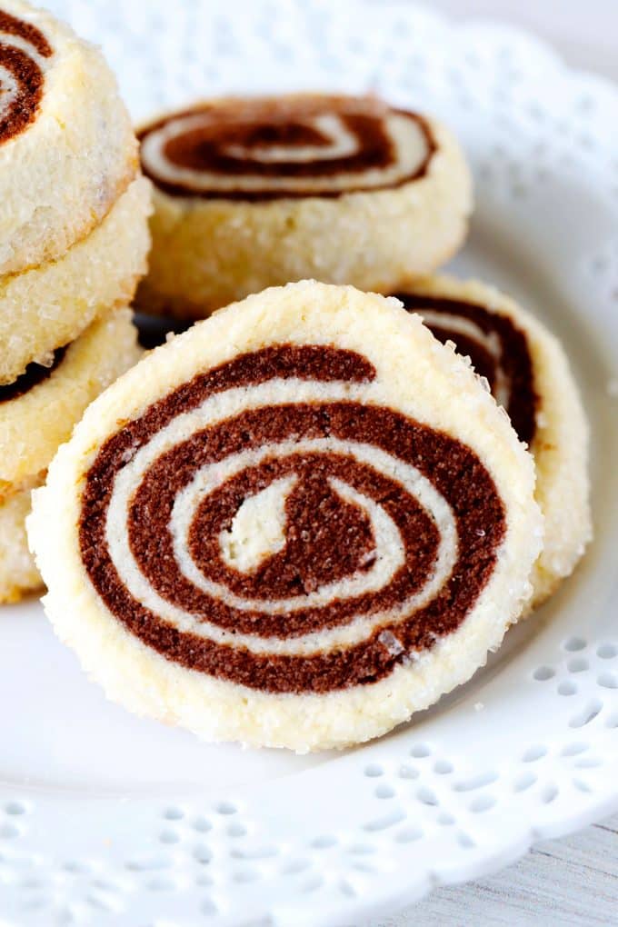 A close up shot of a chocolate pinwheel cookie on a white plate.