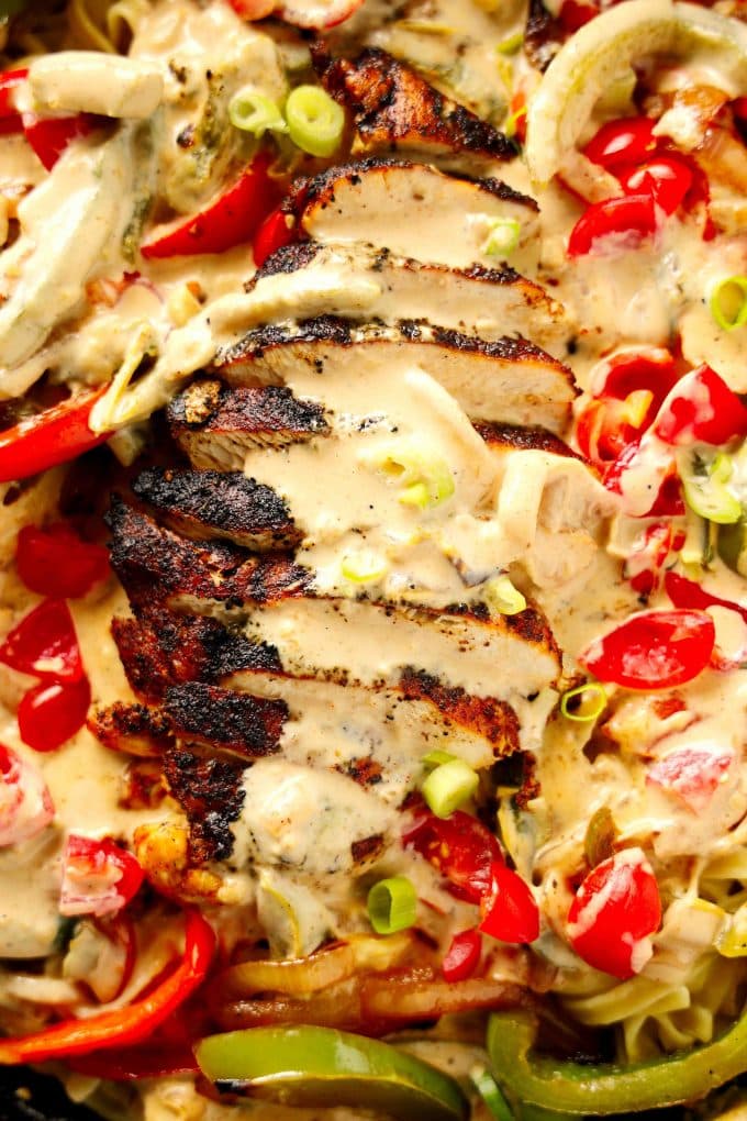 A close up overhead shot of sliced chicken on a bed of cajun alfredo pasta.