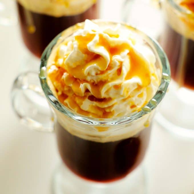 A close up shot of an irish coffee topped with whipped cream and caramel.