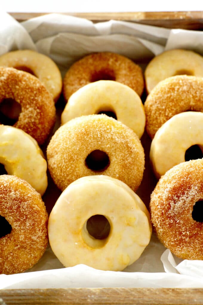 A close up shot of a mix of cinnamon sugar and vanilla glazed air fryer donuts in a box.