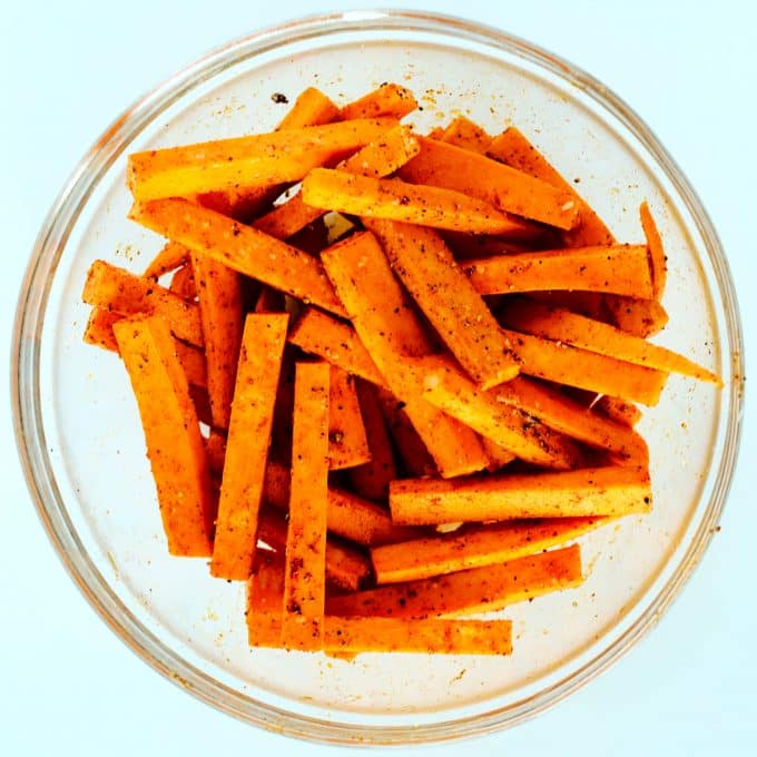 An overhead shot of seasoned, raw sweet potato fries.