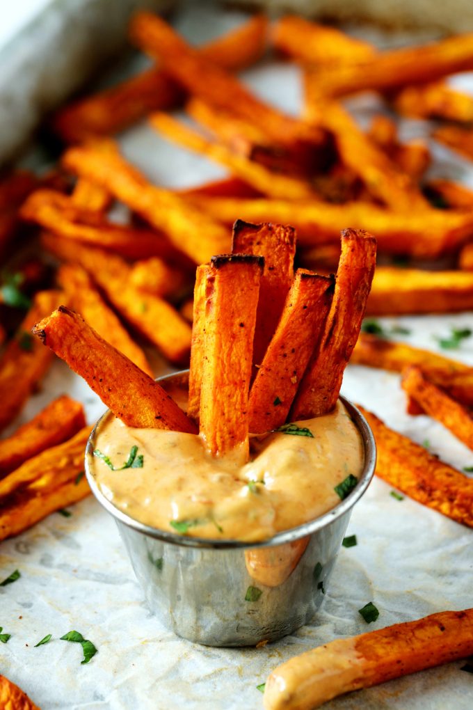 A handful of Sweet Potato Fries dipped in a fry sauce. 