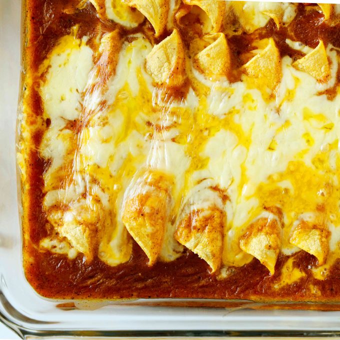 Cheese enchiladas in a baking dish covered with lots of cheese.