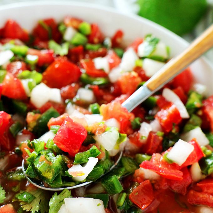 A close up of Pico de gallo with a spoon scooping out some of it.