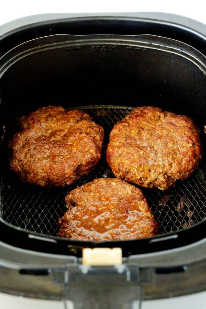 Fully cooked air fryer burgers in the air fryer basket.