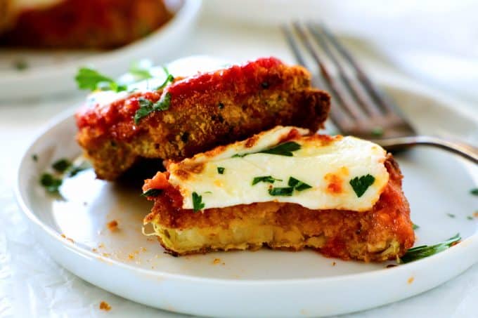 Air Fryer Eggplant Parmesan on a plate with a bite taken out of it and a fork off to the side.